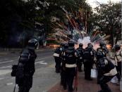 Oficiales de la Policía Nacional Bolivariana se cubren de la explosión de artefactos pirotécnicos lanzados por manifestantes opositores al gobierno durante enfrentamientos en Caracas, Venezuela, el jueves 6 de marzo de 2014. (Foto AP/Fernando Llano)