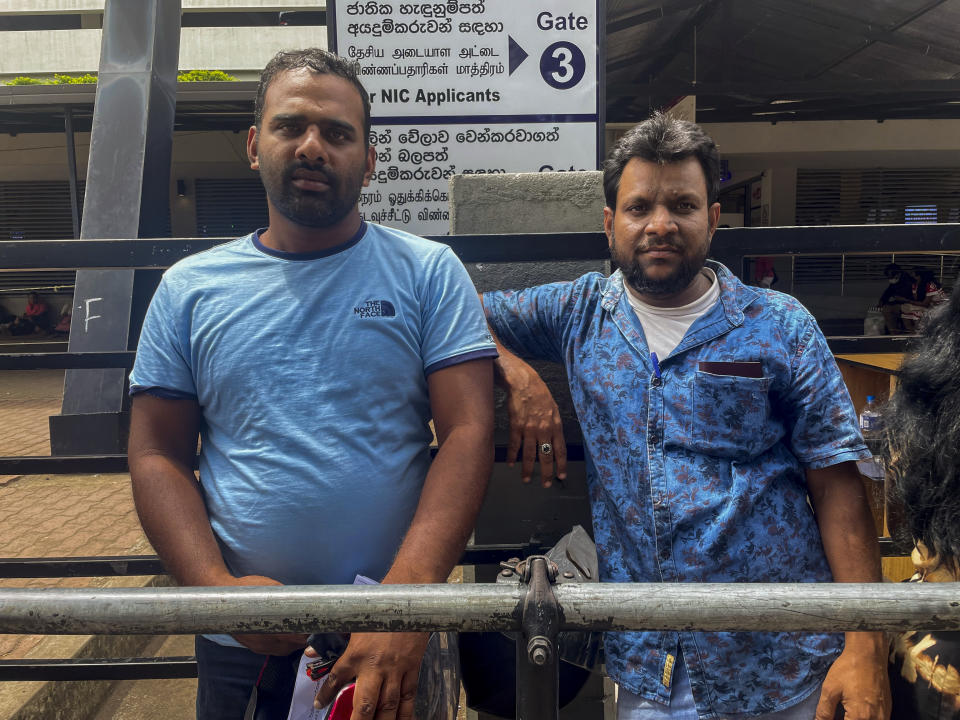Sri Lankan man Mohamed Ishad, left, and his relative Mohamed Fahim wait outside an immigration office to get their passports renewed in Colombo, Sri Lanka, July 14, 2022. With the nation in the throes of its worst economic crisis, Ishad has no job, relies on relatives for financial help and sells vegetables to feed his wife and three children. He wants to go to Japan and find work there so he can send money back home. (AP Photo/Krutika Pathi)