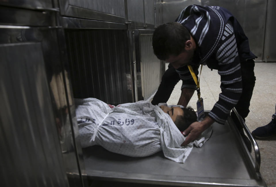 A medic checks the body of 16-year-old Mohammed Jahjouh, who was shot and killed by Israeli troops during a protest at the Gaza Strip's border with Israel, at the morgue of Shifa hospital in Gaza City, Friday, Dec. 21, 2018. (AP Photo/Adel Hana)