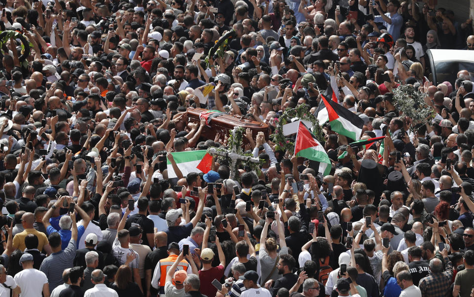 Palestinian mourners wave national flags as they carry the casket of slain  Al-Jazeera journalist Shireen Abu Akleh, during her funeral procession near Jaffa Gate, one of the main gates of the Old City of Jerusalem, on May 13, 2022.