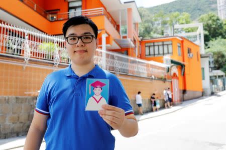 Thomas Lui, who was born two months before the Hong Kong's handover to Chinese rule in 1997, poses with his childhood photo in front of a kindergarten he graduated from in 2003, in Hong Kong, China June 10, 2017. REUTERS/Tyrone Siu