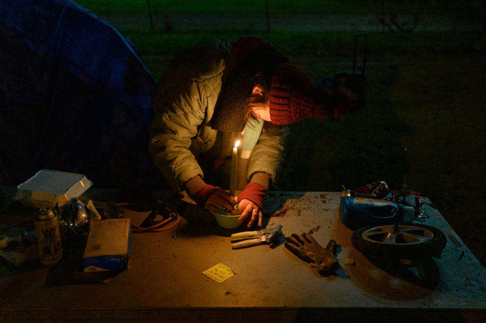 Jessica lights a candle to warm her tent on Dec. 20 after refusing to shelter in the former hospital where she was once treated.<span class="copyright">Rebecca Kiger</span>