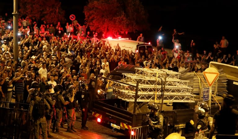 Palestinians celebrate as a truck removes the last of the new security barriers Israel installed at the entrances to Jerusalem's Al-Aqsa mosque compound on July 27, 2017