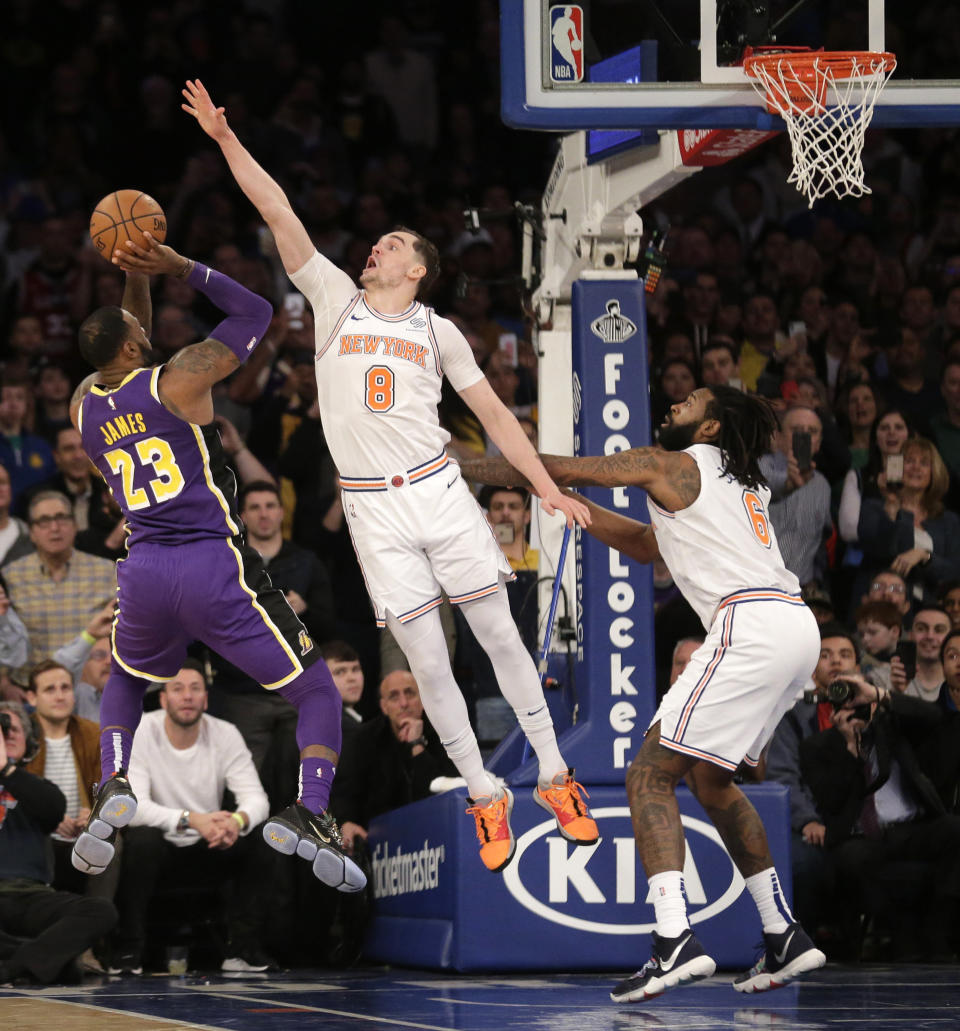 New York Knicks' Mario Hezonja (8), center, blocks what could have been the winning shot by Los Angeles Lakers' LeBron James, left, during the second half of the NBA basketball game, Sunday, March 17, 2019, in New York. (AP Photo/Seth Wenig)