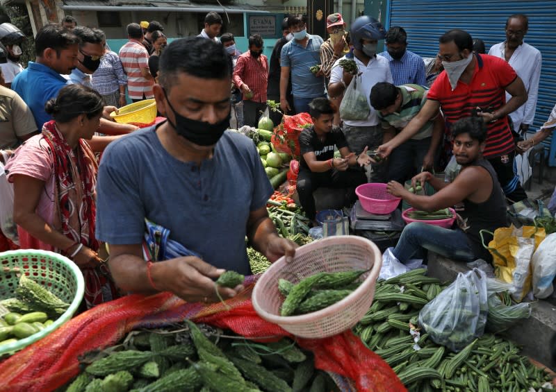 People buy vegetables from roadside stalls before the start of lockdown by West Bengal state government, to limit the spreading of coronavirus disease (COVID-19), in Kolkata