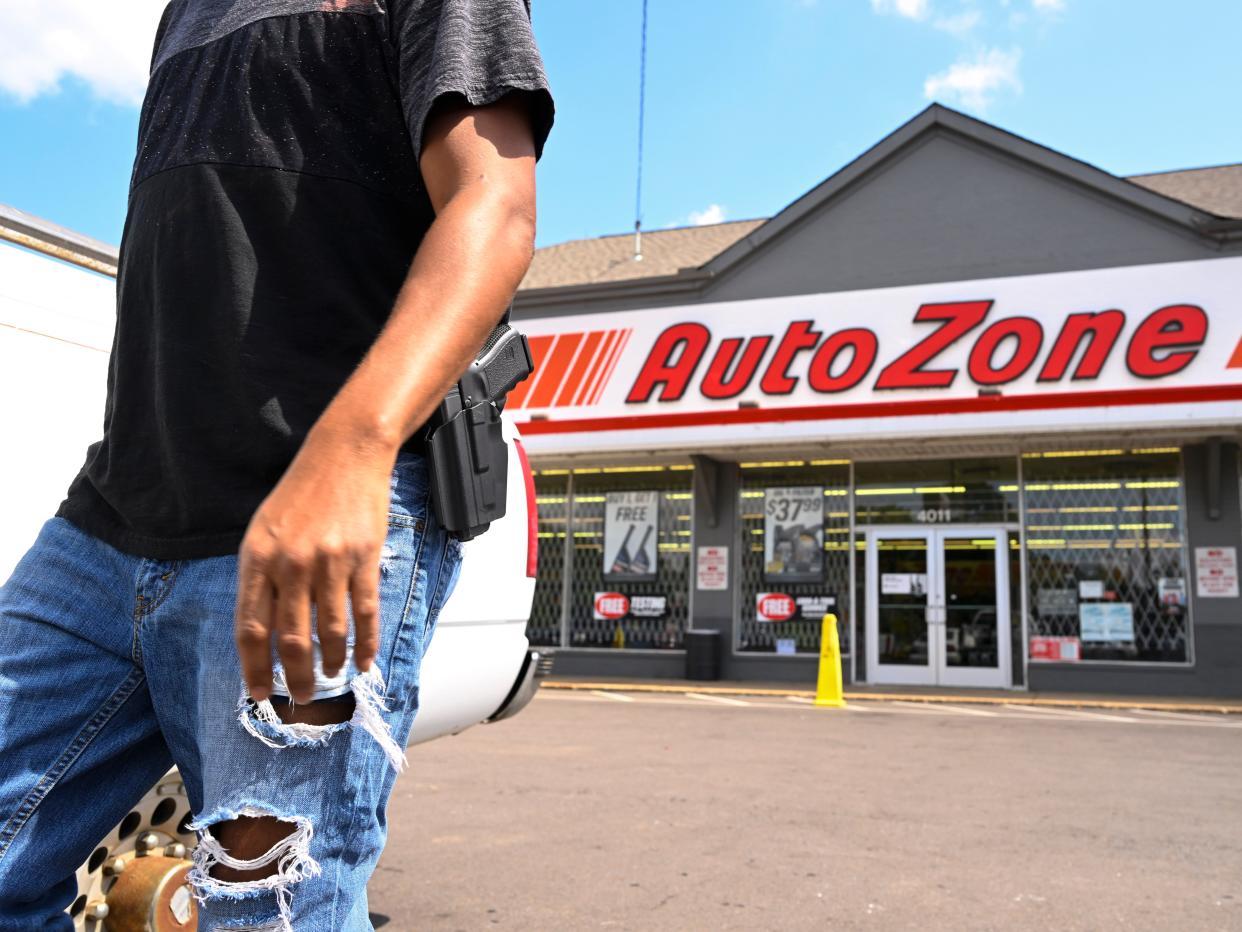 A man carrying a firearm on his hip for protection leaves an Auto Zone store, Thursday, Sept. 8, 2022, in Memphis, Tenn. On Wednesday afternoon, a man entered the Auto Zone and live streamed himself as he shot a person who lived through the incident.