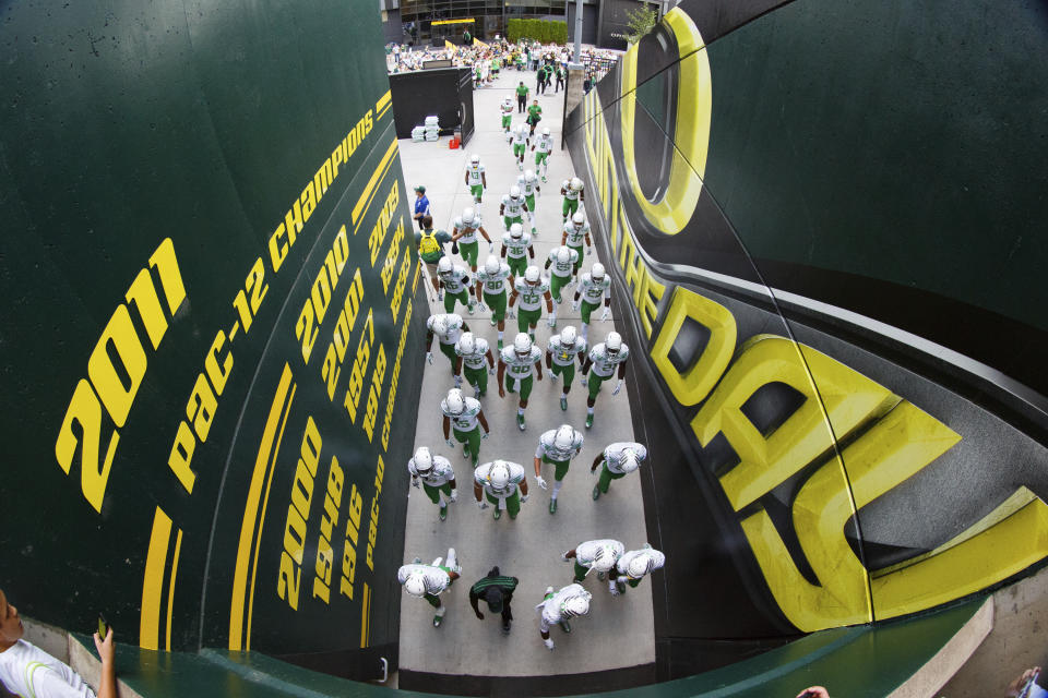 FILE - The Oregon football team walks through a tunnel before an NCAA college football game against South Dakota in Eugene, Ore., Saturday, Aug. 30, 2014. Dealing a crushing combination to the Pac-12 on Friday, Aug. 4, 2023, the Big Ten announced Oregon and Washington would be joining the conference next August, and the Big 12 completed its raid of the beleaguered league by adding Arizona, Arizona State and Utah. (AP Photo/Ryan Kang, File)