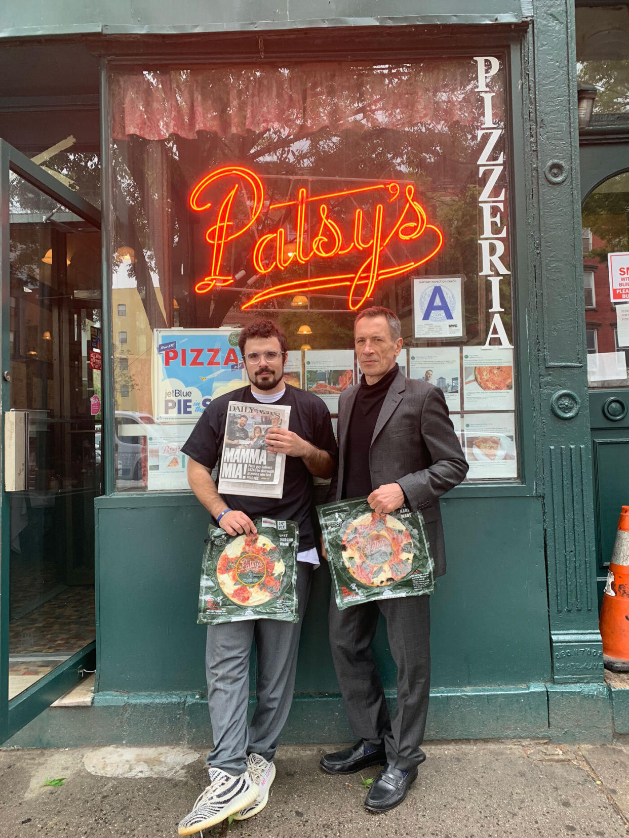 Adem Brija and his father, Frank Brija, stand outside the original Pasty's location in East Harlem, holding a copy of their front page photo on the NY Daily News. (Credit: Adem Brija)