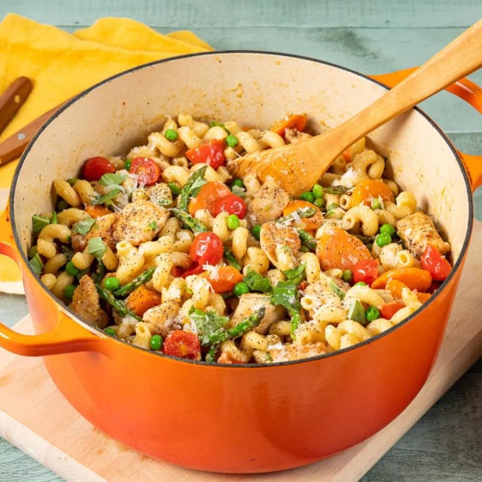 chicken primavera in orange dutch oven with wooden spoon