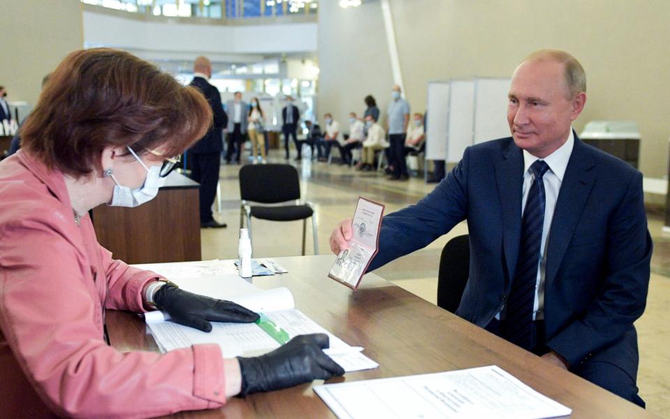 Russian President Vladimir Putin shows his passport to a member of an election commission - Alexei Druzhinin, Sputnik, Kremlin Pool Photo via AP