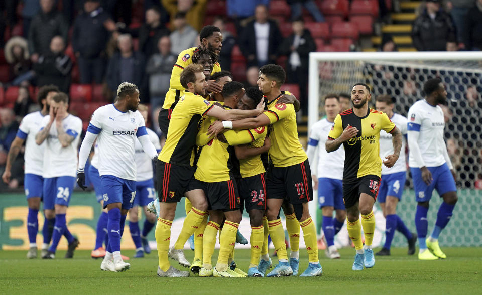 Watford's Tom Dele-Bashiru, center, is mobbed by his team-mates as he celebrates scoring his side's first goal of the game DURING the English FA Cup third round soccer match between Watford and Tranmere Rovers at Vicarage Road, Watford, England, Saturday, Jan. 4, 2020. (John Walton/PA via AP)