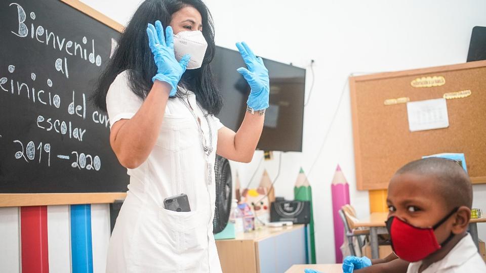 Maestra y niño con mascarilla en un salón de clase en La Habana