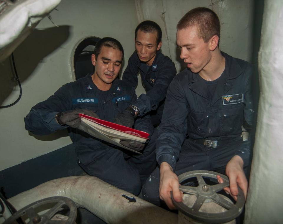 Machinist’s Mate 3rd Class Duane Hilumeyer, left; Machinist’s Mate 3rd Class Kexian Li, center; and Machinist’s Mate Fireman Jacob Tylisz close a valve to maintain accumulator steam pressure on a catapult aboard the Nimitz-class aircraft carrier USS Carl Vinson, September 24, 2014.