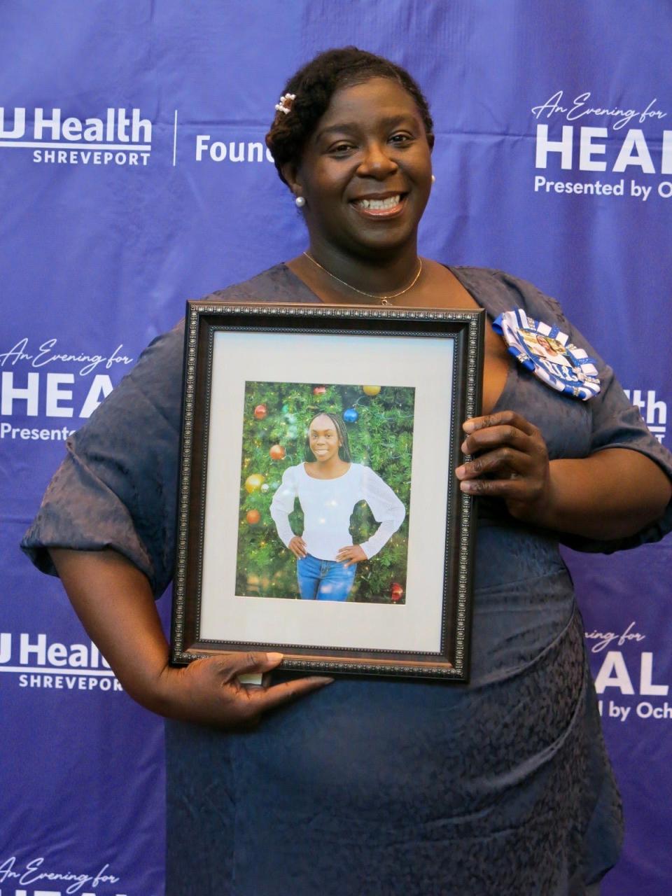 Shanna Jones, arriving at an Evening For Healers, holds a photo in memory of her daughter Kerrington Jones at the LSUHS "Evening for Healers" on August 31, 2023.