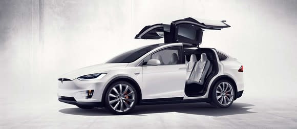 White Tesla Model X vehicle with rear doors open.