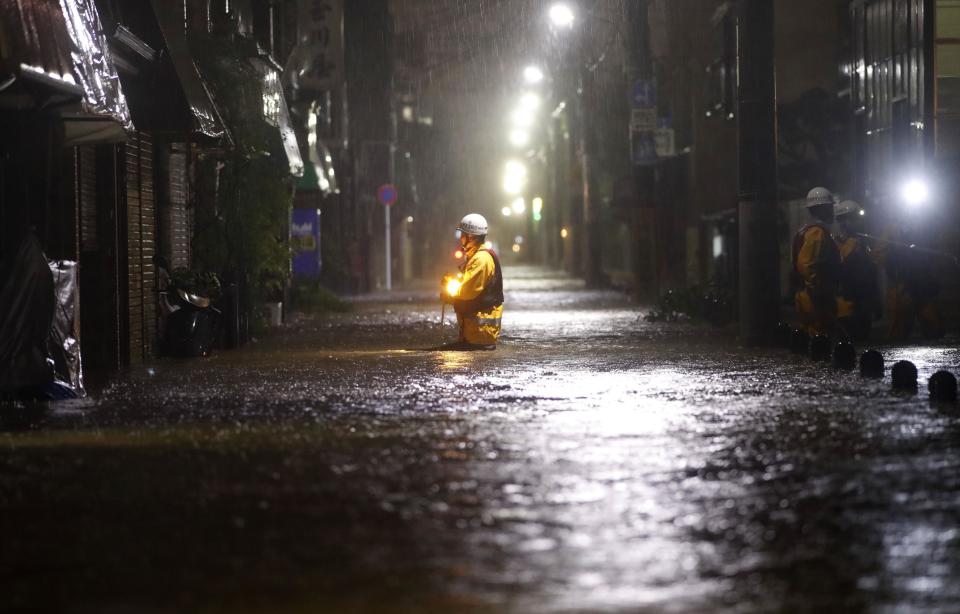 A firefighter makes his way through flooded street in the residential area hit by Typhoon Hagibis, in Tokyo, Saturday, Oct. 12, 2019. A heavy downpour and strong winds pounded Tokyo and surrounding areas on Saturday as a powerful typhoon forecast as the worst in six decades approached landfall, with streets and train stations deserted and shops shuttered.(Kyodo News via AP)