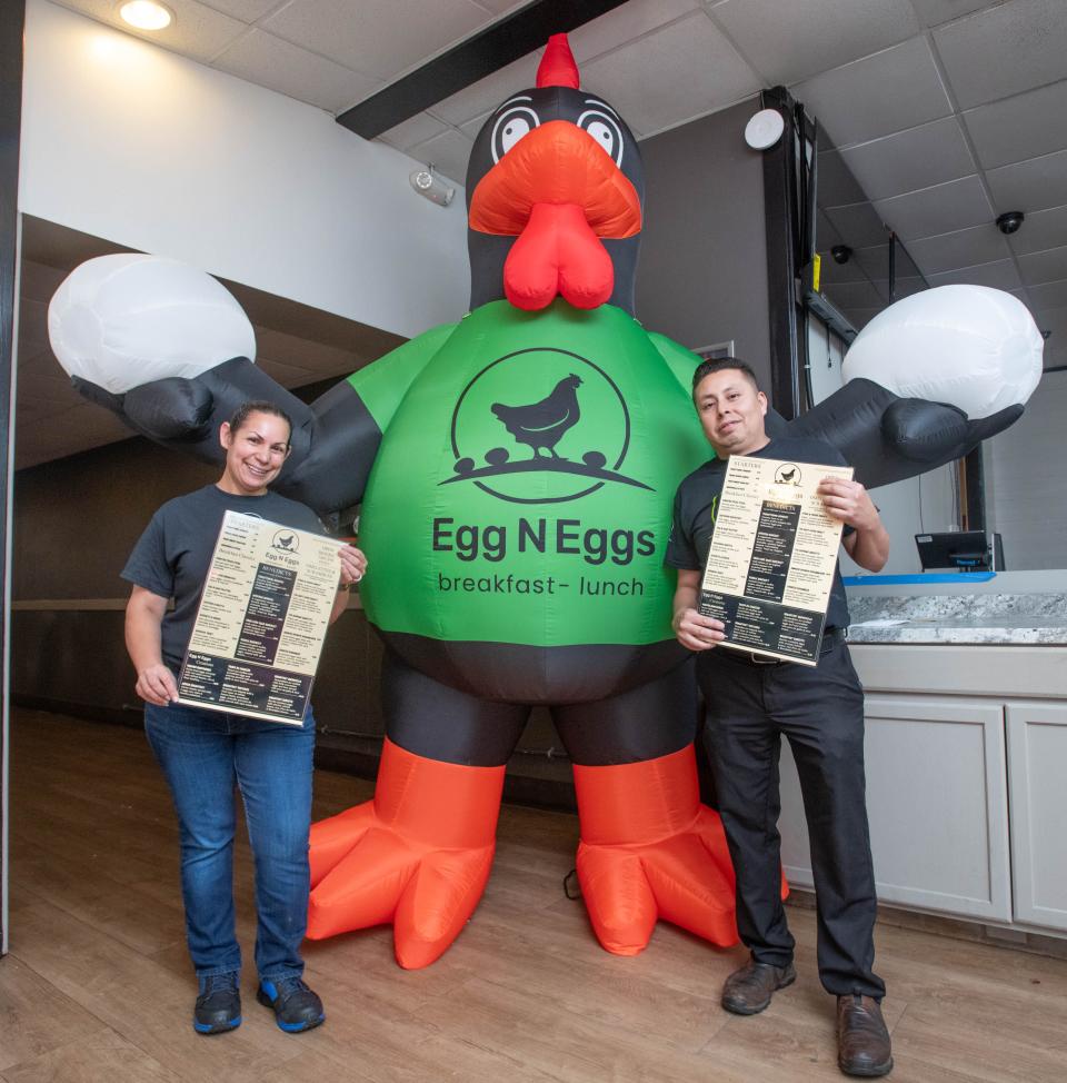 Owners Reina Medina, left, and Gerardo Zentle hold menus as they pose in front of an inflatable chicken sign at their new Egg N Eggs restaurant, which will share the building with their Xiscali Mexican Taqueria at 19 N. Navy Blvd. in Pensacola on Monday, Nov. 13, 2023. Egg N Eggs will be opening soon.