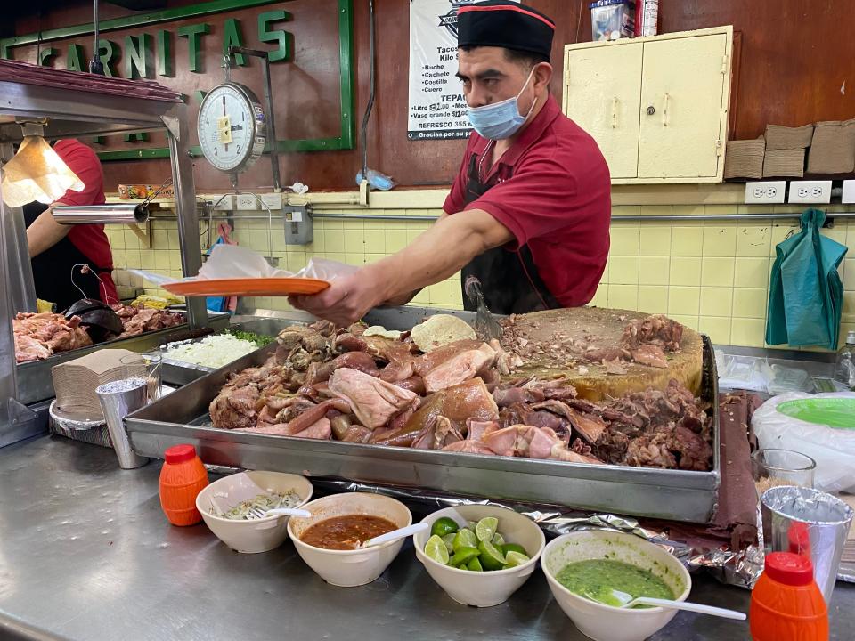 Man in a red shirt standing above a tray of mixed meats