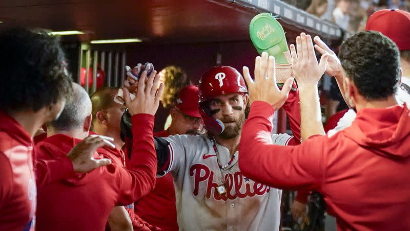 Philadelphia Phillies’ Bryce Harper celebrates in the dugout after scoring on a wild pitch during the seventh inning in Game 3 of the baseball NL Championship Series against the Arizona Diamondbacks in Phoenix on Thursday, Oct. 19, 2023.