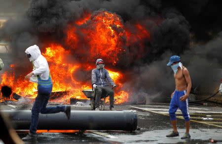 Demonstrators build a fire barricade on a street during a rally against Venezuela's President Nicolas Maduro in Caracas. REUTERS/Christian Veron