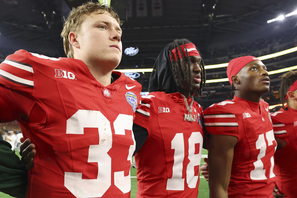 Ohio State quarterback Devin Brown (33), wide receiver Marvin Harrison Jr. (18) and wide receiver Carnell Tate (17) stand together after the team's loss to Missouri in the Cotton Bowl NCAA college football game Friday, Dec. 29, 2023, in Arlington, Texas. (AP Photo/Richard W. Rodriguez)