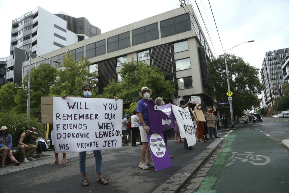 Protesters gather outside the Park Hotel calling for the release of refugees being detained inside the hotel in Melbourne, Australia, Friday, Jan. 7, 2022. The world’s No. 1-ranked tennis player Novak Djokovic is also being held there after border officials canceled his visa last week over a vaccine requirement. (AP Photo/Hamish Blair)