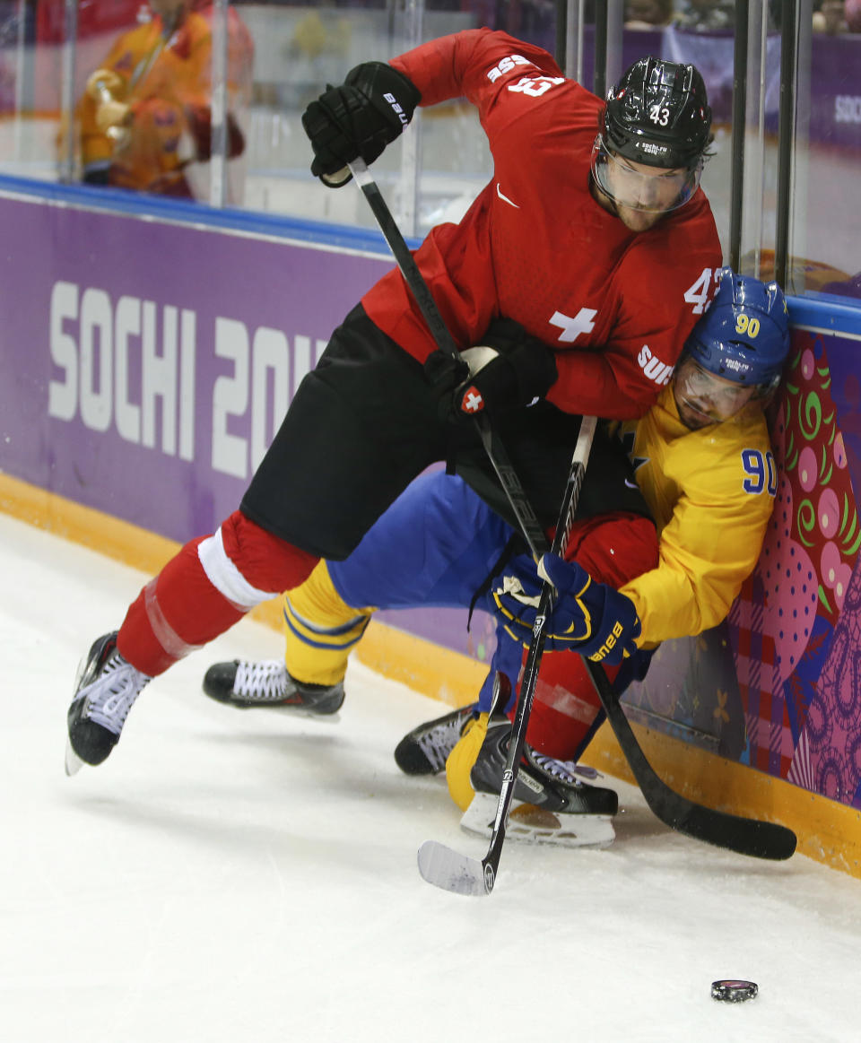 Switzerland forward Morris Trachsler fights for the puck against Sweden forward Marcus Johansson in the first period of a men's ice hockey game at the 2014 Winter Olympics, Friday, Feb. 14, 2014, in Sochi, Russia. (AP Photo/Mark Humphrey)