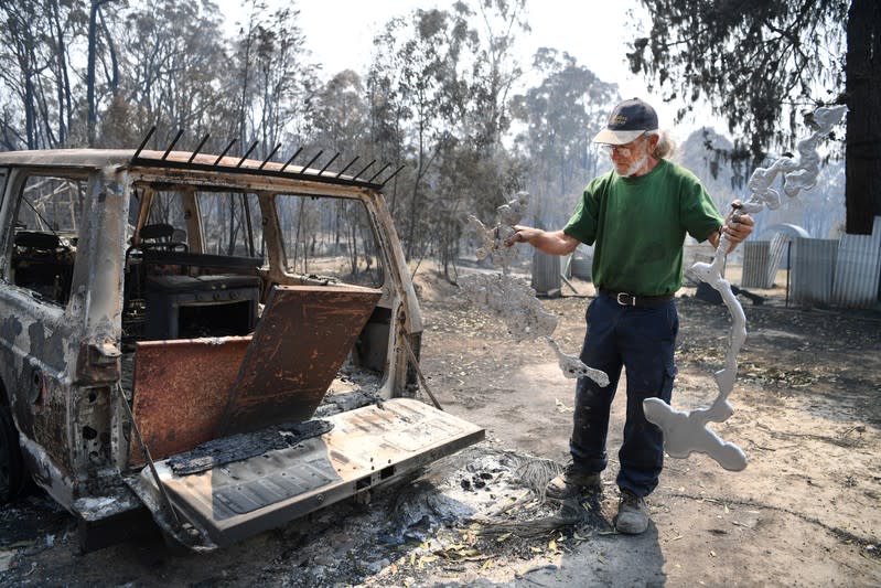 Thomas Eveans holds melted aluminium as he inspects the remains of his house which was destroyed by a bushfire in Torrington, near Glen Innes