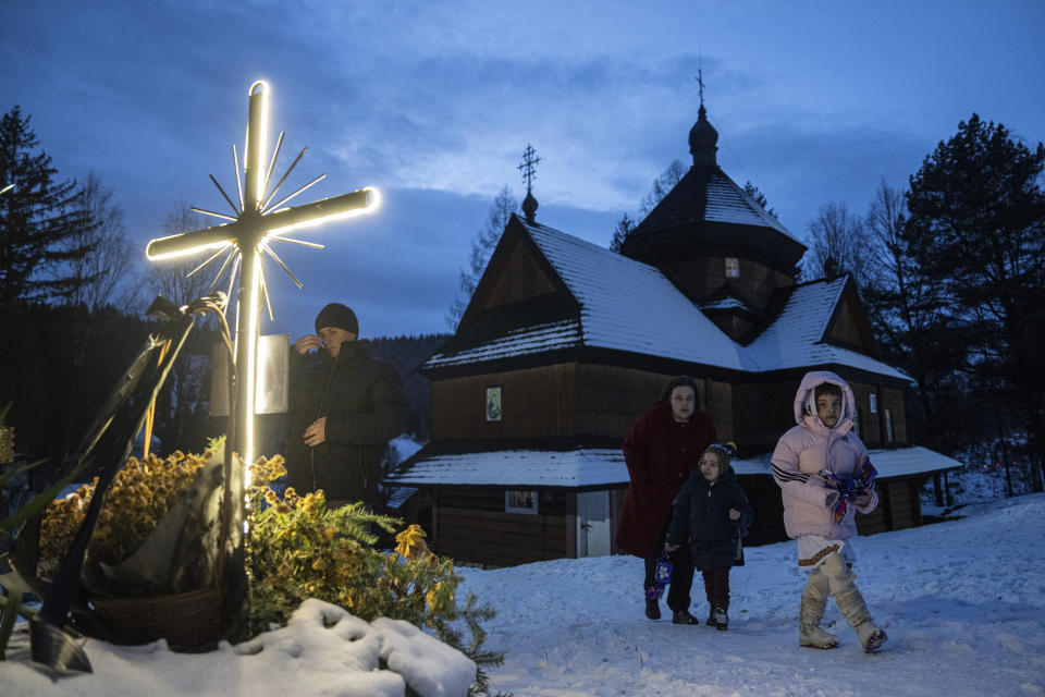 A woman with her children walk after church Christmas service in Kryvorivnia village, Ukraine, Sunday, Dec. 24, 2023. (AP Photo/Evgeniy Maloletka)