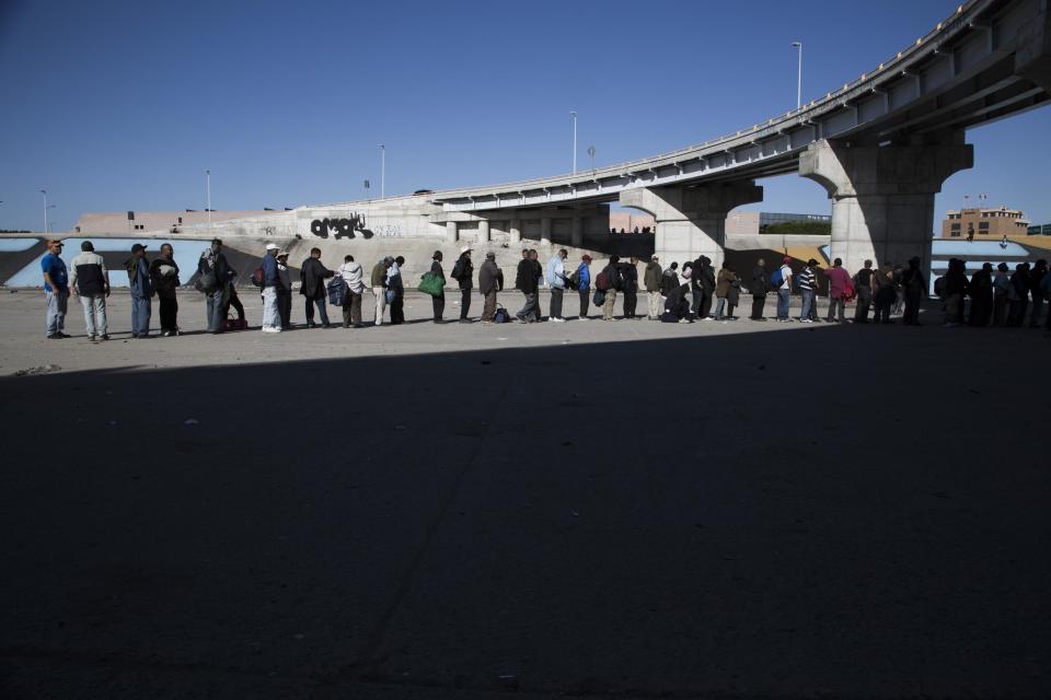 Personas hacen fila para recibir comida de un grupo de caridad en un sector conocido como "El Bordo", cerca de un canal en Tijuana, en México, el viernes 21 de febrero de 2014. Numerosas personas quedan atrapadas en la frontera del lado mexicano incapaces de regresar a sus lugares de origen ni a Estados Unidos, de donde fueron deportados. (AP Photo/Alex Cossio)