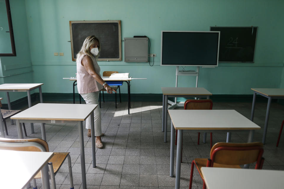 A woman checks that desks are placed apart from each other at the Daniele Manin school in Rome, Thursday, Aug. 27, 2020. Despite a spike in coronavirus infections, authorities in Europe are determined to send children back to school. They want to narrow learning gaps between haves and have-nots that deepened during virus lockdowns – and to get their parents back to work. (Cecilia Fabiano/LaPresse via AP)
