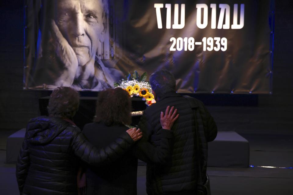 People show respect pass by the coffin of Amos Oz during his funeral service in Tel Aviv, Israel, Monday, Dec. 31, 2018. Israeli author Amos Oz, one of the country's most widely acclaimed writers and a pre-eminent voice in its embattled peace movement, died on Friday after a battle with cancer, his family announced. He was 79. (AP Photo/Ariel Schalit)