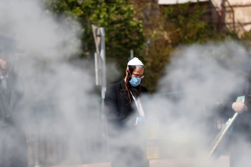 An Ultra-Orthodox Jewish man wears a face mask for protection related to the coronavirus as he burns leaven in the Mea Shearim neighbourhood of Jerusalem ahead of the Jewish holiday of Passover