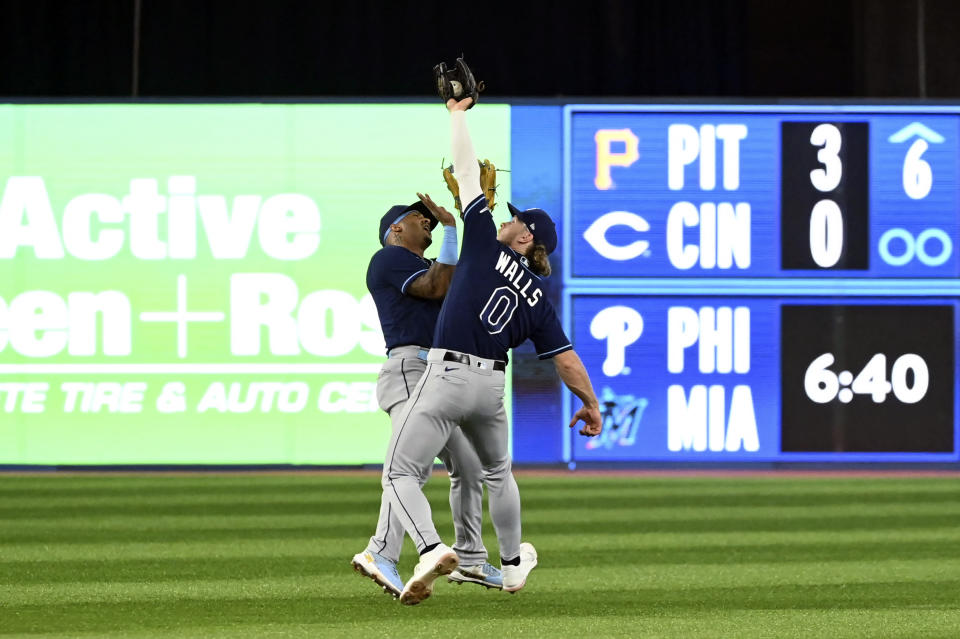 Tampa Bay Rays second baseman Taylor Walls catches a fly ball off the bat of Toronto Blue Jays Santiago Espinal while avoiding a collision with teammate Wander Franco, left, in the third inning of the first baseball game of a doubleheader in Toronto, Tuesday, Sept. 13, 2022. (Jon Blacker/The Canadian Press via AP)