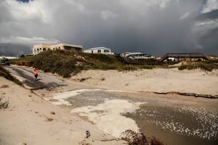 A man takes a picture on the dunes of the closed Crescent Beach before Hurricane Dorian in St. Augustine