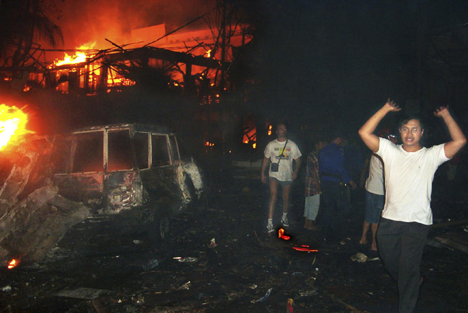 FILE - Residents and foreign tourists evacuate the scene of a bomb blast in Kuta, Bali, Indonesia, on Oct. 13, 2002. A car bomb outside Sari Club and a suicide bombing at nearby Paddy's Pub in Kuta, Bali, on Oct. 12, 2002 killed 202 people, mostly foreign tourists. (AP Photo/Radar Bali, File)