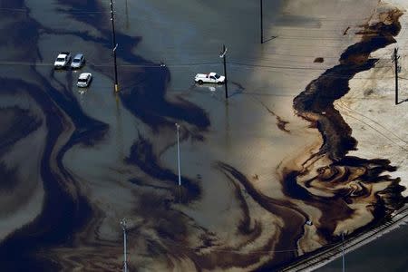 FILE PHOTO: Vehicles sit amid leaked fuel mixed in with flood waters caused by Tropical Storm Harvey in the parking lot of Motiva Enterprises LLC in Port Arthur, Texas, U.S. on August 31, 2017. REUTERS/Adrees Latif/File Photo