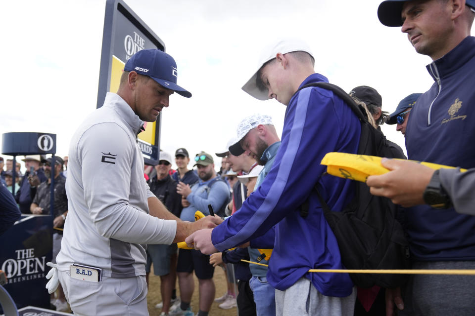 Bryson DeChambeau of the US signs autographs during a practice round at the British Open golf championship on the Old Course at St. Andrews, Scotland, Wednesday July 13, 2022. The Open Championship returns to the home of golf on July 14-17, 2022, to celebrate the 150th edition of the sport's oldest championship, which dates to 1860 and was first played at St. Andrews in 1873. (AP Photo/Alastair Grant)
