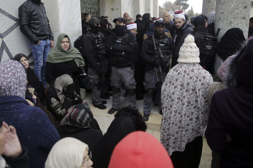 Israeli police stands at the door to the Dome of the Rock mosque confronted by Palestinians, Monday, Jan. 14, 2019. Scuffles broke out at the Dome of the Rock in Jerusalem's Old City on Monday after guards at the mosque refused to allow an Israeli policeman to enter for a routine security check because he was wearing a Jewish skullcap known as a kippah. (AP Photo/Mahmoud Illean)