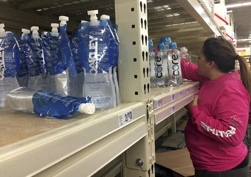 In this Thursday, Dec. 15, 2016 photo, a woman reaches for bottles of water after a recent back-flow incident in the industrial district according to a city news release, at H-E-B in Corpus Christi, Texas. (Gabe Hernandez/Corpus Christi Caller-Times via AP)