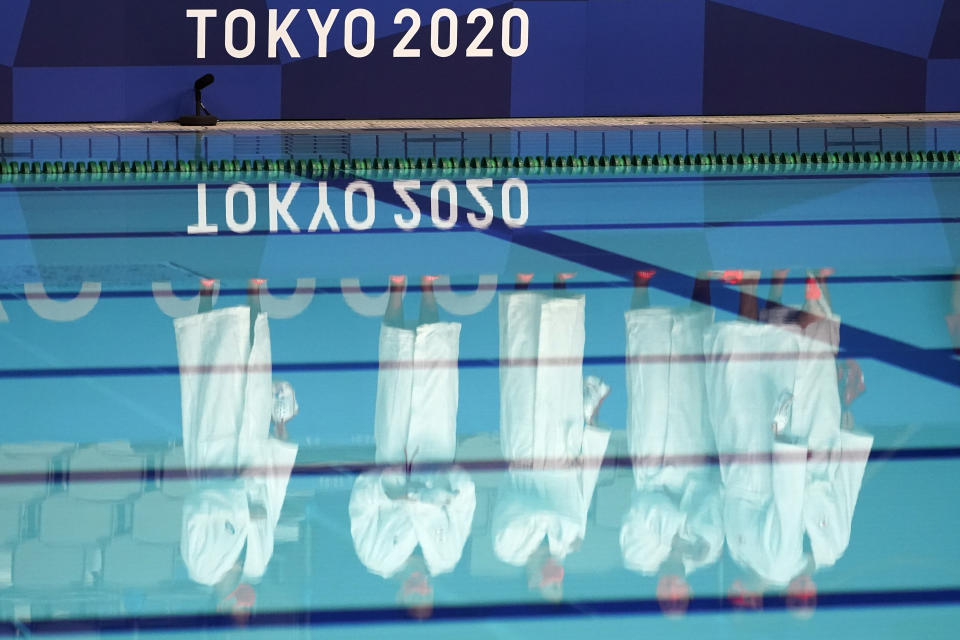 Members of the Japanese women's water polo team are reflected on the water as they are introduced before a preliminary match against the United States at the 2020 Summer Olympics, Saturday, July 24, 2021, in Tokyo, Japan. (AP Photo/Mark Humphrey)