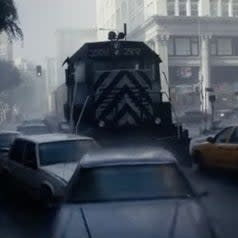 A train runs through a city street, pushing cars away
