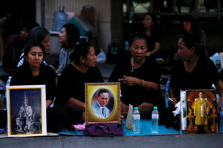 People sit behind portraits of Thailand's late King Bhumibol Adulyadej in Bangkok, Thailand, October 14, 2016. REUTERS/Chaiwat Subprasom