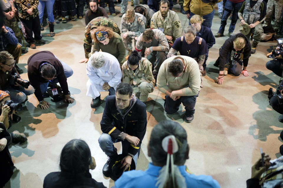 Wesley Clark Jr. and other veterans kneel in front of Leonard Crow Dog during a forgiveness ceremony at the Four Prairie Knights Casino &amp; Resort on the Standing Rock Sioux Reservation on Monday.