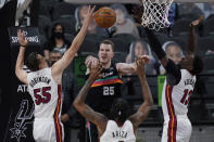 San Antonio Spurs center Jakob Poeltl (25) passes the ball as he is pressured by Miami Heat defenders Duncan Robinson (55), Trevor Ariza (8) and Bam Adebayo (13) during the second half of an NBA basketball game in San Antonio, Wednesday, April 21, 2021. (AP Photo/Eric Gay)