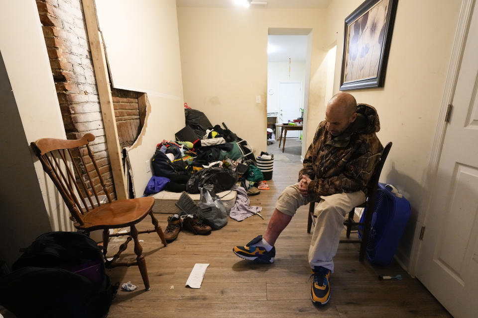 Anthony Kelly sits in his living room after checking his leg, which is suffering from tendonitis after he suffered a fall from his bicycle, Tuesday, May 2, 2023, in Baltimore. Kelly has been using help from the Baltimore City Health Department's harm reduction program RV, which is used to address the opioid crisis, which includes expanding access to medication assisted treatment by deploying a team of medical staff to neighborhoods with high rates of substance abuse and offering buprenorphine prescriptions. (AP Photo/Julio Cortez)