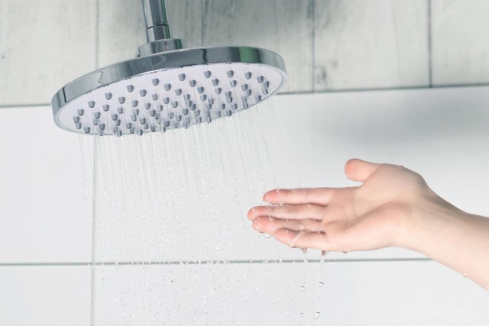 A hand touches water coming out of a shower