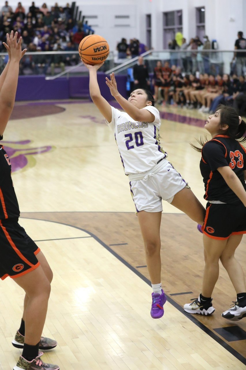 Kirtland Central's Tyra Yazzie dribbles into the paint and puts up a shot against Gallup's Rylie Whitehair (left) and Adriell Thomas (33) in the fourth quarter of the District 1-4A championship game on Saturday, February 25, 2023 at Bronco Arena.