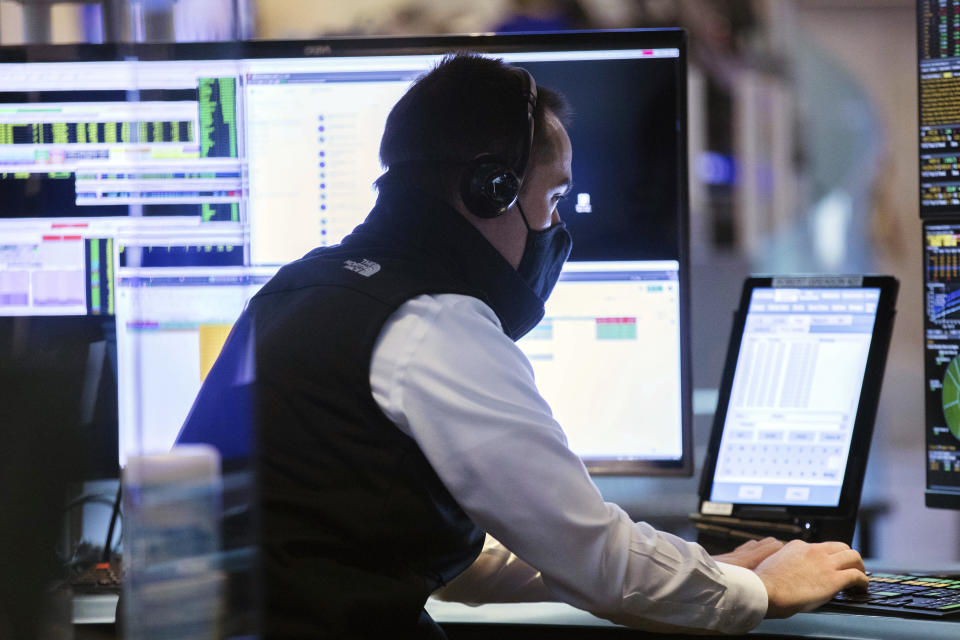 In this photo provided by the New York Stock Exchange, a trader wears a protective face mask as he works on the partially reopened trading floor, Tuesday, May 26, 2020, in New York. Stocks surged on Wall Street in afternoon trading Tuesday, driving the S&P 500 to its highest level in nearly three months, as hopes for economic recovery overshadow worries about the coronavirus pandemic. (Colin Zimmer/New York Stock Exchange via AP)