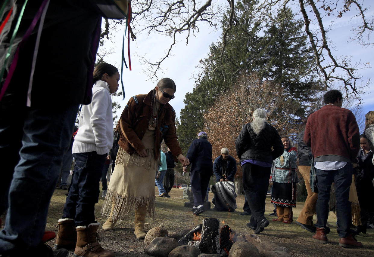 Mashpee Wampanoag tribe members sprinkle tobacco over a fire during a Native American Thanksgiving celebration on Nov. 23, 2013, at the Old Indian Meeting House in Mashpee. (Photo: Boston Globe via Getty Images)